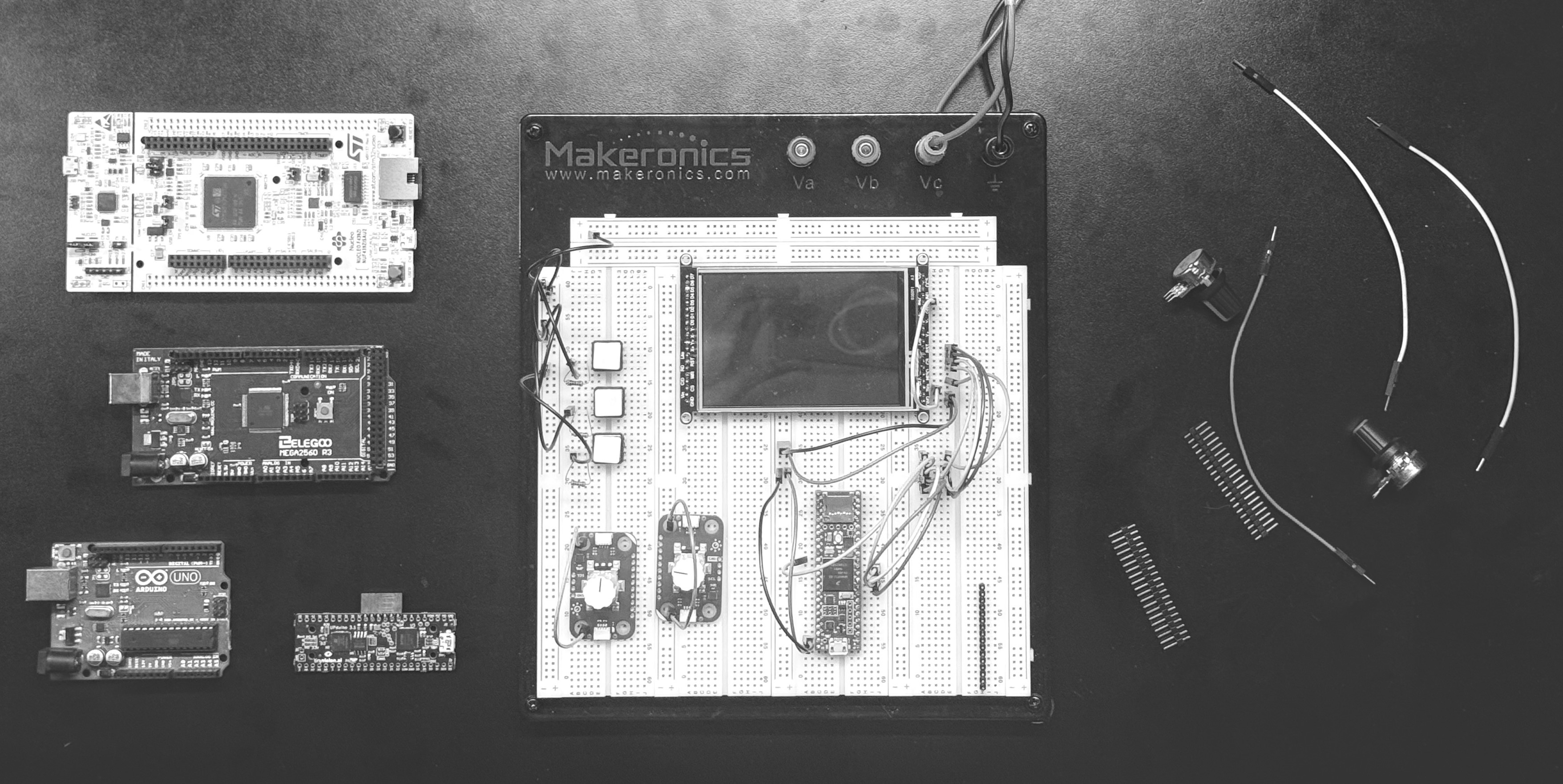 An STM32, ATmega2560 (Mega-compatible), Arduino Uno, and Tinyduino (FPGA) surrounding a Makeronics breadboard. Center: Adafruit-HX8357D display driven by a Teensy 4.1.